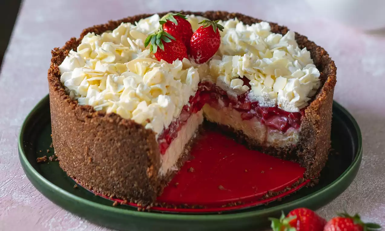 Trojvrstvová jahodová torta s čokoládovým sušienkovým okrajom, vrstvou vanilkového krému, jahodovej polevy a šľahačky, ozdobená čerstvými jahodami