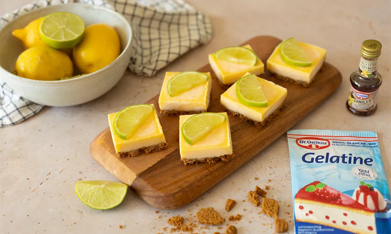 Carrés de lime crémeux aux teintes jaunes et vertes, posés sur une base biscuitée marron et sur une planche en bois rustique