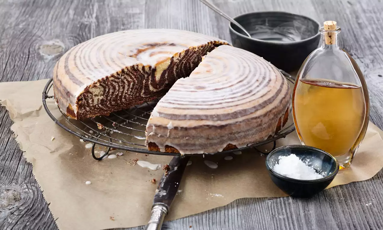 Zebrakuchen mit Guss zeigt saftige schwarz-weiße Marmorierung und glänzenden Schokoladenguss auf einem weißen Teller
