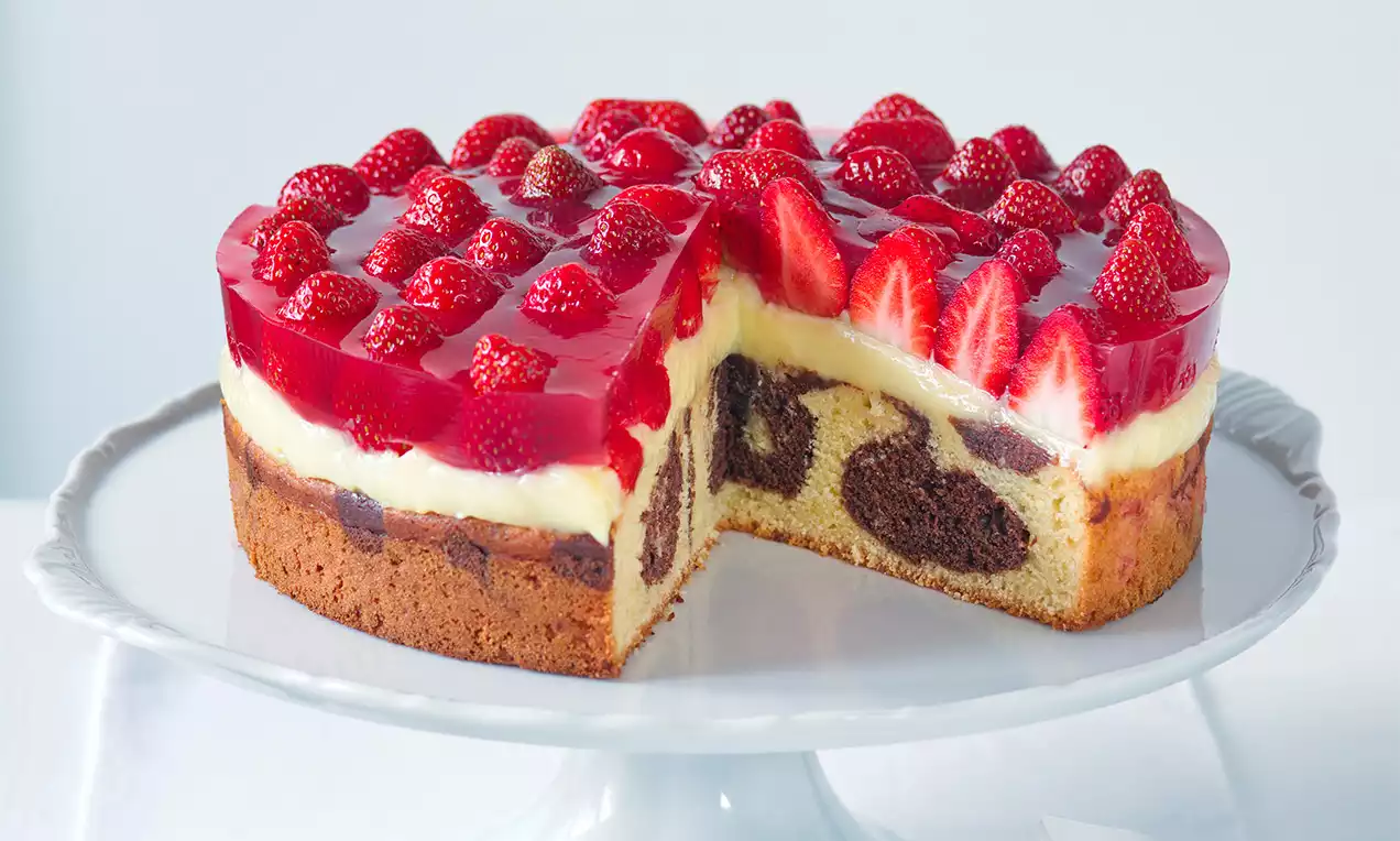 Jahodový mramorovaný dort s vrstvou lesklej červenej želé a čerstvých jahôd na svetlom krémovom základe, rezná časť odhaľuje kakaové víry